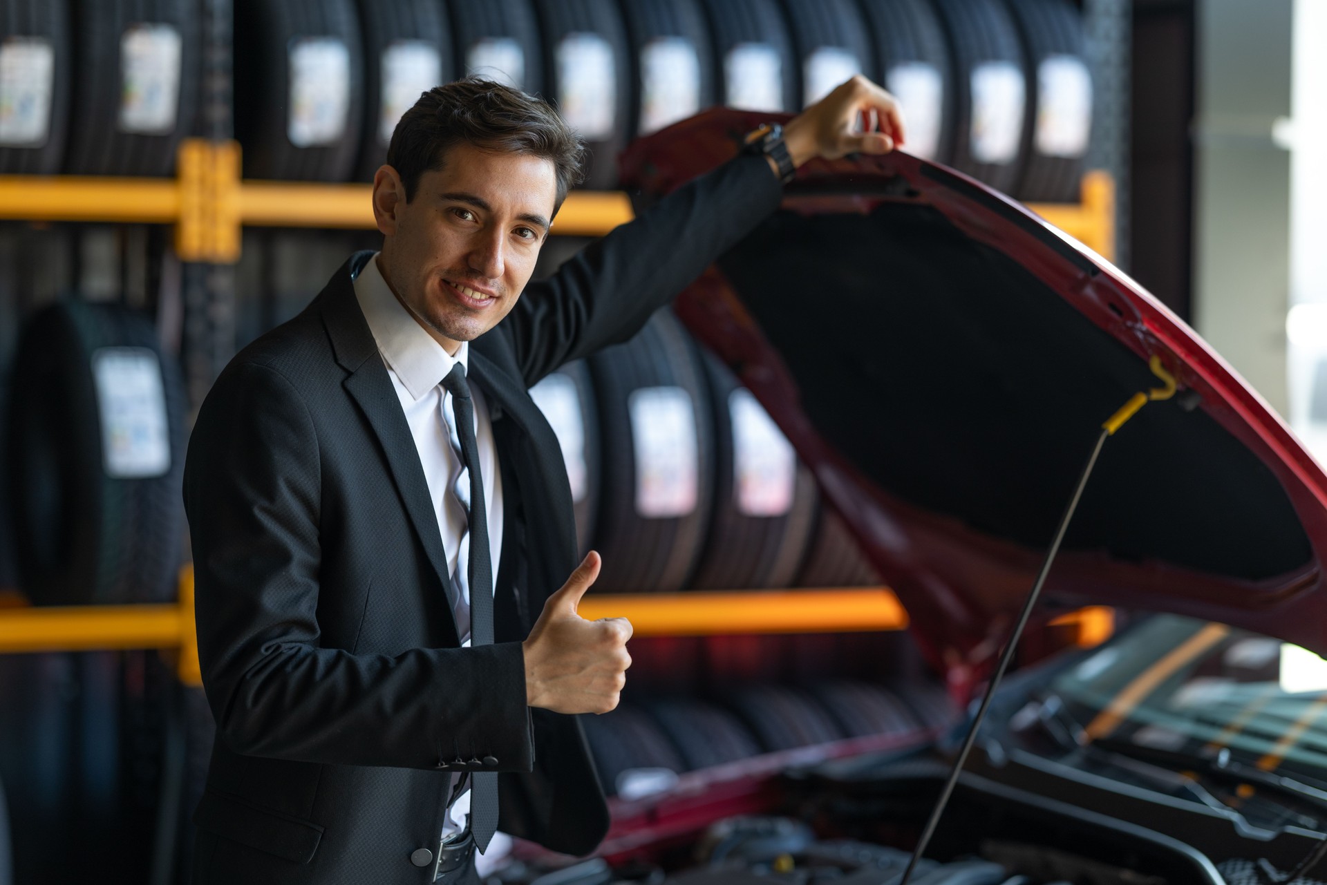 Confident Businessman Showing Thumbs Up at Car Repair Shop